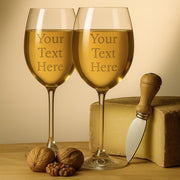 Two wine glasses with text placeholder, cheese, knife, and nuts on a wooden surface.