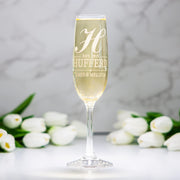 Champagne flute with engraved text and white tulips on a light background