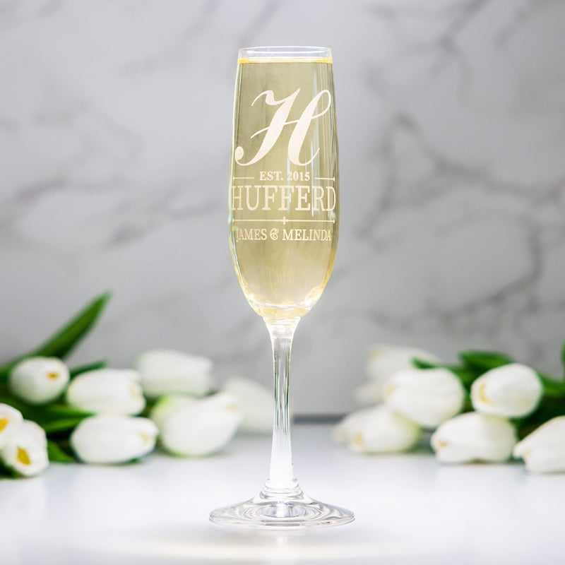 Champagne flute with engraved text and white tulips on a light background