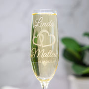 Personalized champagne flute with engraved names and date on a light background