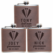 Three leather-wrapped flasks with engraved names and dates on a white background