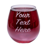 A stemless wine glass with custom text engraved on the side, filled with red wine.