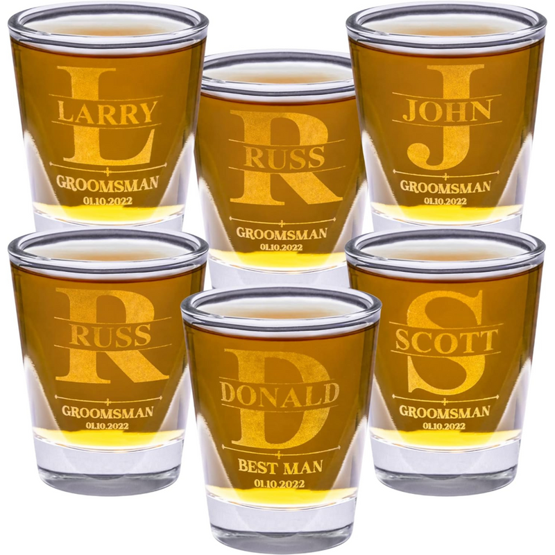 Set of personalized shot glasses with names and roles engraved, filled with a yellow liquid.