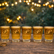 Five shot glasses with 'Peterson' branding on a wooden surface with a festive background.