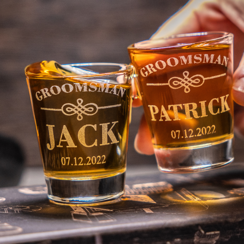 Engraved groomsman whiskey shot glasses with personalized names and wedding date.